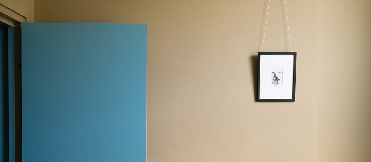 Eine im beige Ton gestrichene Wand und eine in blau lackierte Tür dazu