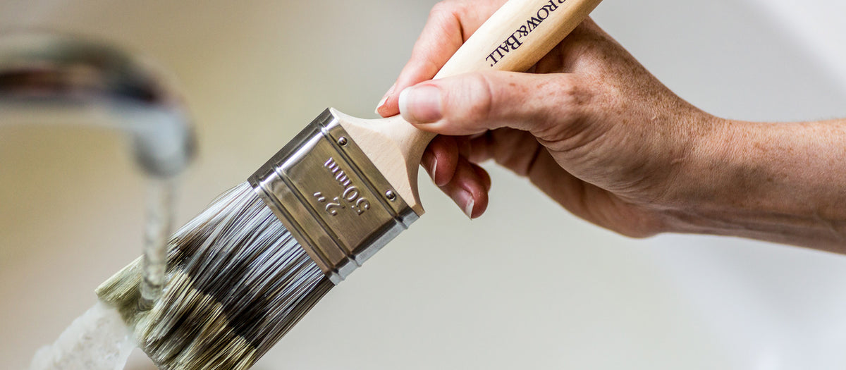 Ein Farrow and Ball Flachpinsel der mit Wasser ausgespült wird 