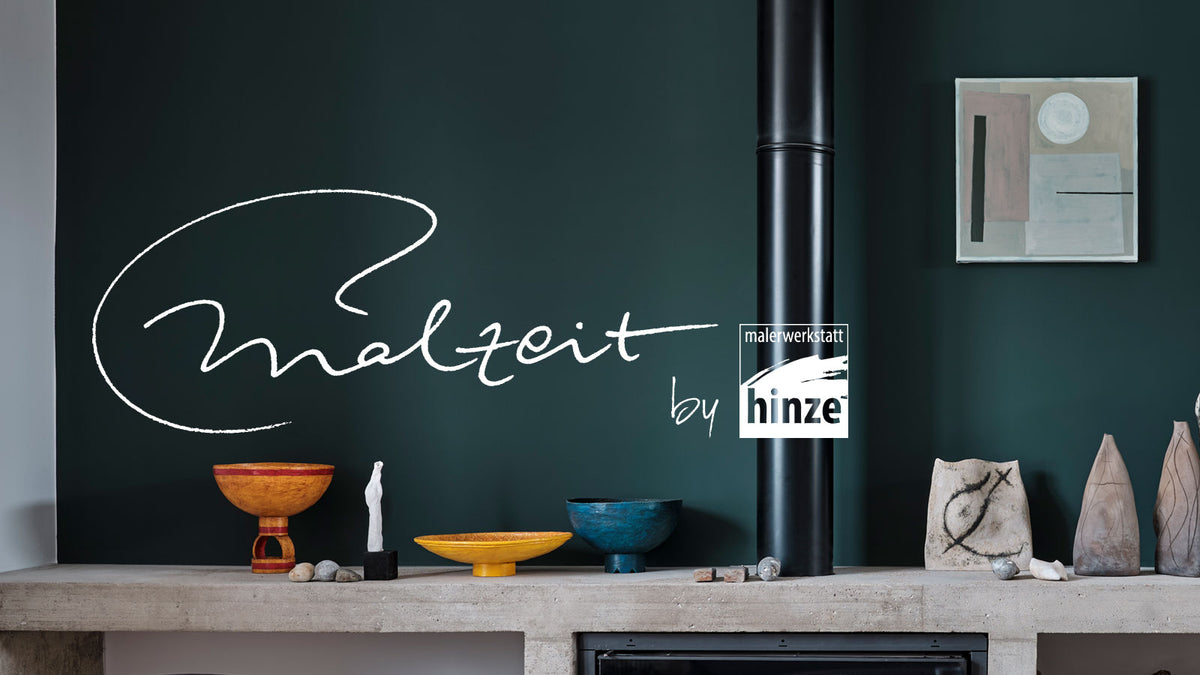 eine Blaue Wand mit einem Sideboard aus Beton und Deko Elementen auf dem das Malzeit Logo zu sehen ist.  